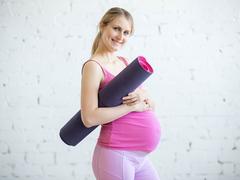 Schwangere Frau mit Jogamatte
