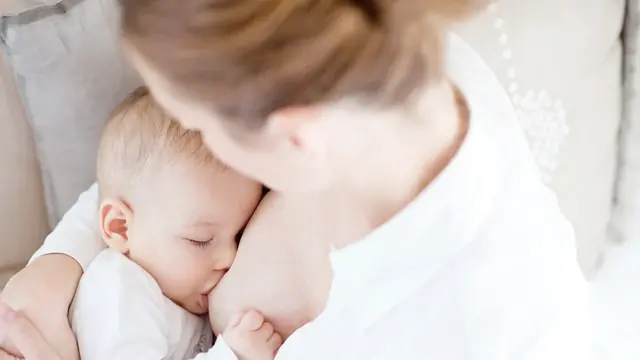 Frau stillt Baby im Arm