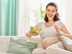 Schwangere Frau isst kleine Mahlzeit